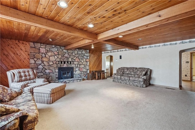 living area with carpet floors, beam ceiling, recessed lighting, wooden walls, and a stone fireplace