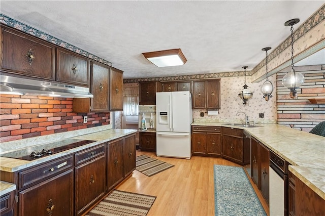 kitchen with white refrigerator with ice dispenser, under cabinet range hood, oven, a sink, and wallpapered walls