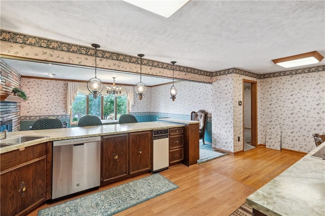 kitchen with dishwasher, wallpapered walls, light wood-style flooring, light countertops, and a textured ceiling