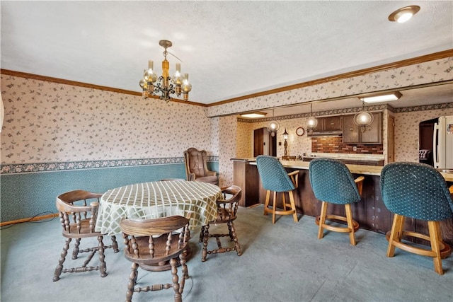 dining room with wallpapered walls, ornamental molding, a chandelier, carpet, and a textured ceiling