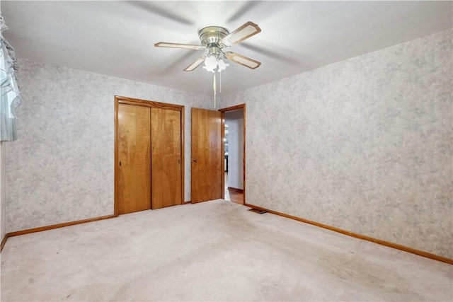 unfurnished bedroom featuring carpet flooring, ceiling fan, a closet, and baseboards