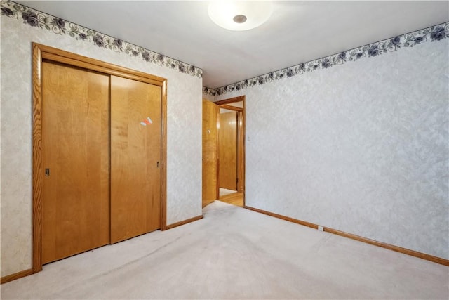 unfurnished bedroom featuring carpet floors, a closet, and baseboards