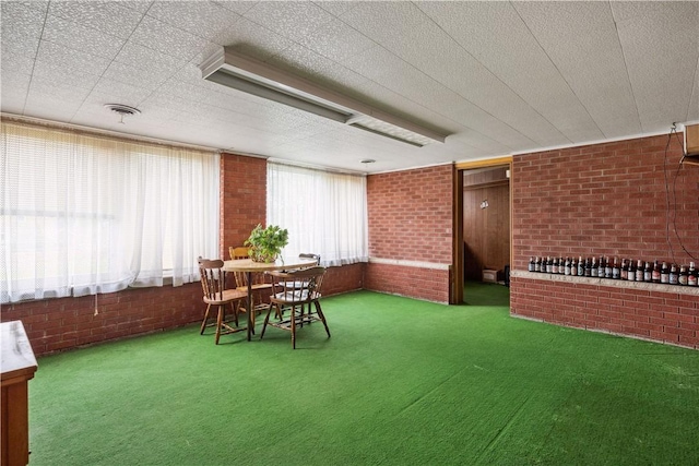 carpeted dining area with brick wall