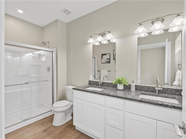 full bath with a shower stall, wood finished floors, toilet, and double vanity