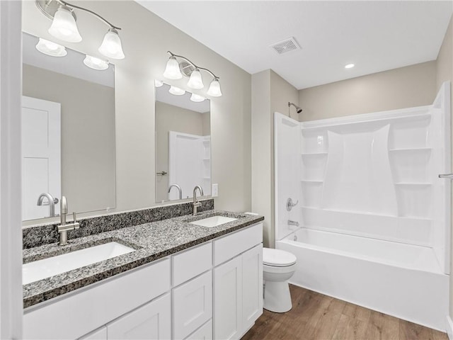 full bath with wood finished floors, toilet, bathing tub / shower combination, and double vanity