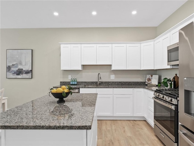 kitchen with appliances with stainless steel finishes, a sink, white cabinetry, and recessed lighting