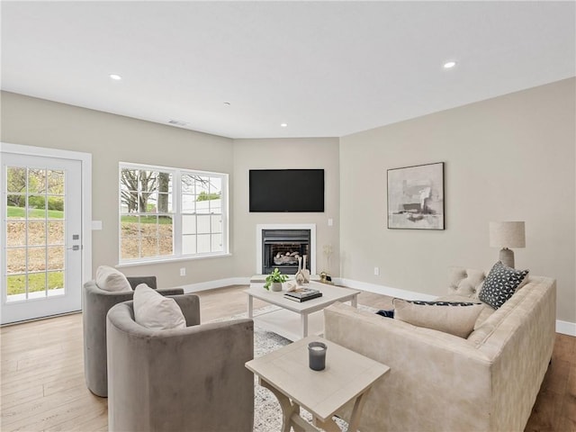 living area featuring light wood-style floors, recessed lighting, a fireplace, and baseboards