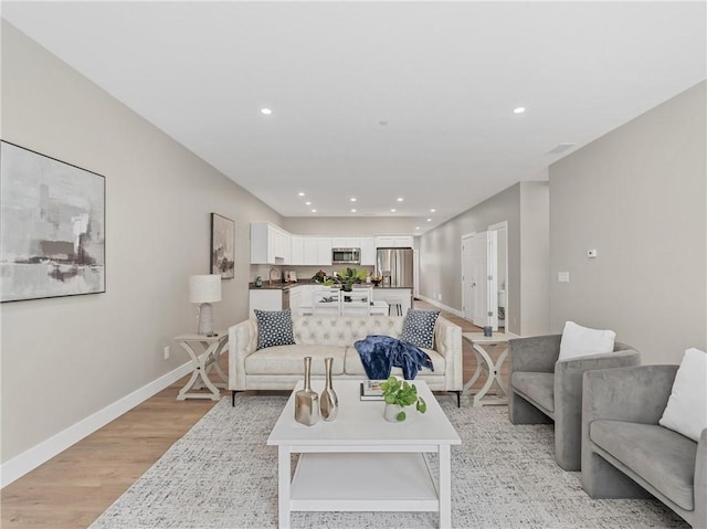 living area with light wood finished floors, recessed lighting, and baseboards