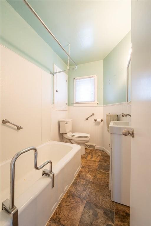 full bathroom featuring toilet, stone finish flooring, vanity, and shower / tub combination