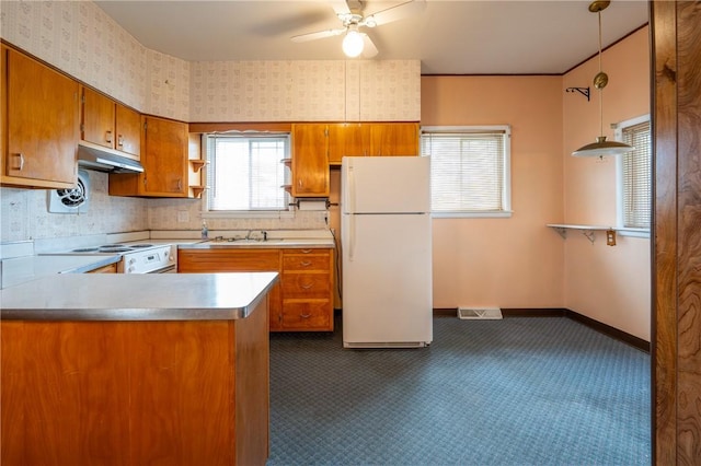 kitchen featuring freestanding refrigerator, brown cabinets, dark colored carpet, range with electric cooktop, and ceiling fan