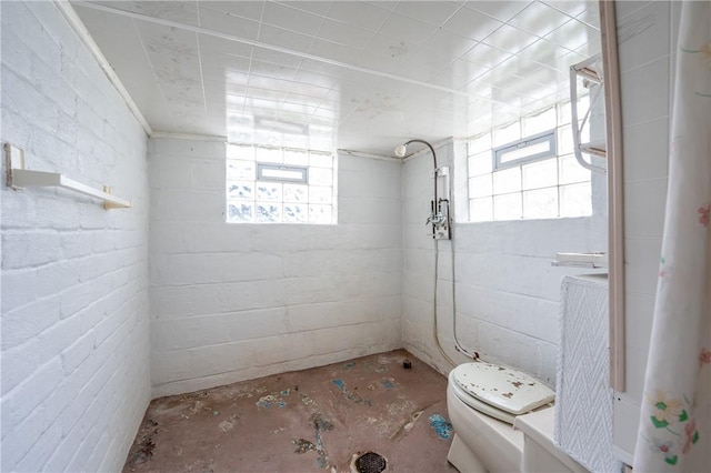 full bathroom featuring concrete flooring, tiled shower, and toilet