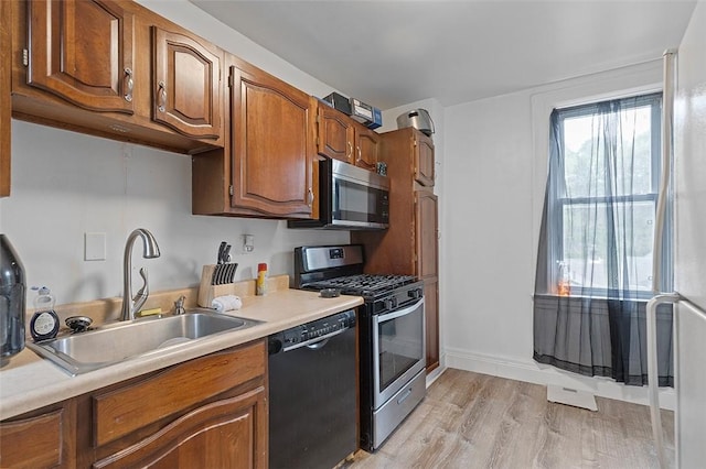 2633 S 18th St, Mount Oliver, PA 15210 - kitchen featuring appliances with stainless steel finishes, a sink, light countertops, light wood finished floors, and brown cabinetry