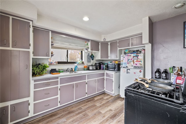 2841 Mary St, South Side, PA 15203 - kitchen with black gas range oven, a sink, freestanding refrigerator, stainless steel microwave, and light wood finished floors