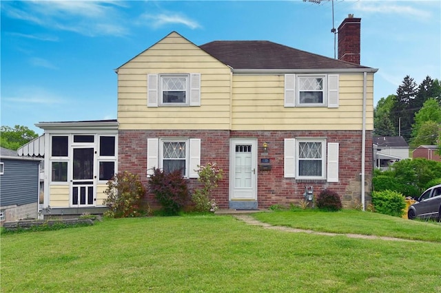view of front facade featuring a chimney, a front yard, and brick siding