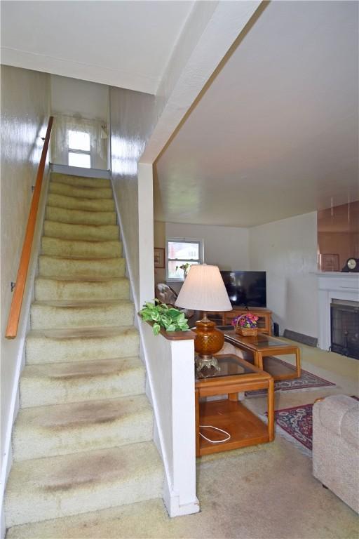 stairway with plenty of natural light, carpet, and a fireplace