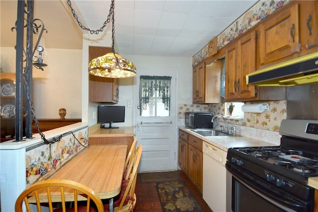 kitchen with stainless steel gas stove, white dishwasher, under cabinet range hood, a sink, and brown cabinetry