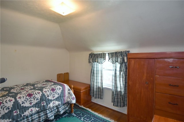 bedroom with wood finished floors and lofted ceiling