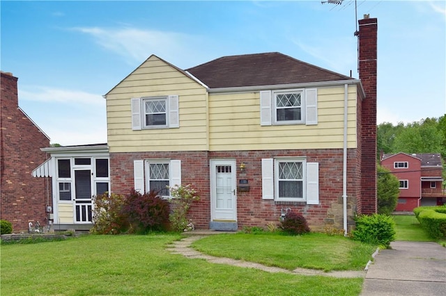view of front of home featuring a chimney, a front yard, brick siding, and a shingled roof