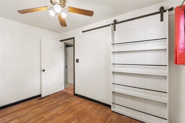 1024 Maine Ave, Hopewell Twp Bea, PA 15001 - unfurnished bedroom featuring a barn door, wood finished floors, baseboards, and ceiling fan