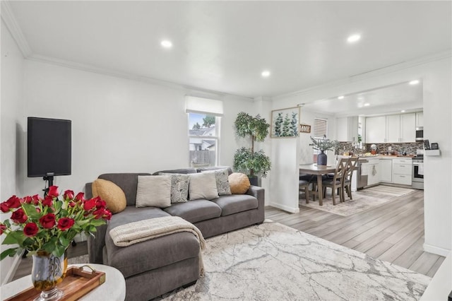 living area with ornamental molding, light wood-style flooring, and recessed lighting