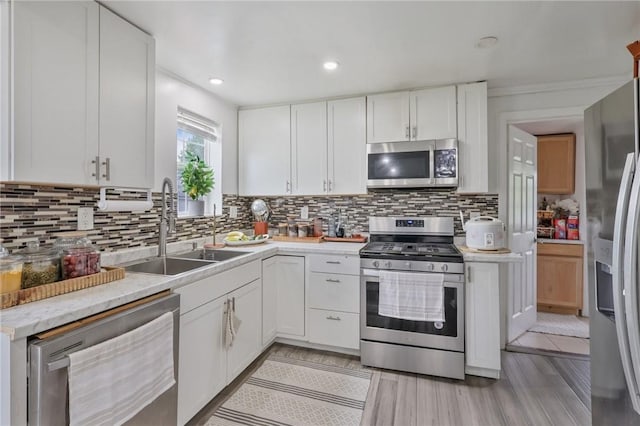 kitchen featuring stainless steel appliances, a sink, light countertops, decorative backsplash, and recessed lighting