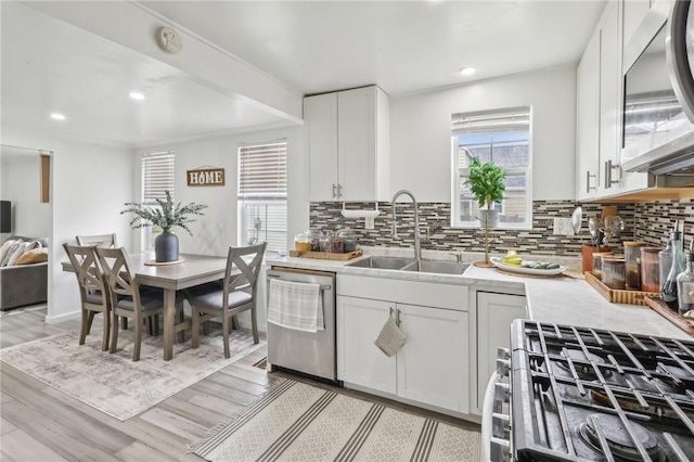 kitchen featuring stainless steel appliances, a sink, light countertops, tasteful backsplash, and recessed lighting
