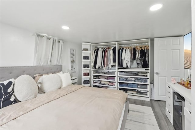 bedroom with wood finished floors, recessed lighting, a closet, and a dry bar