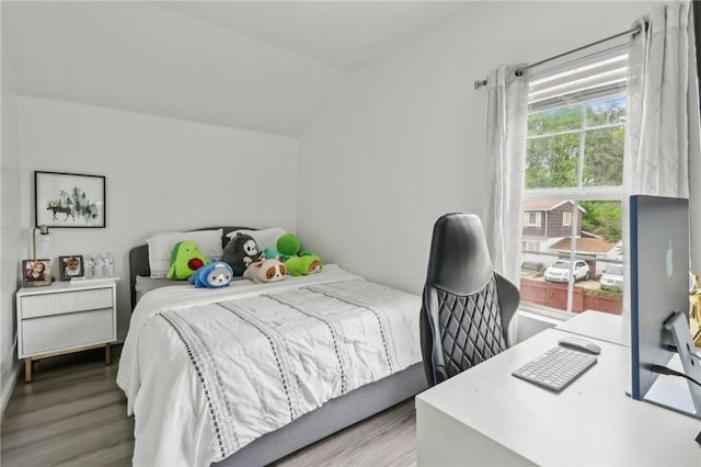 bedroom featuring wood finished floors, an office area, and lofted ceiling