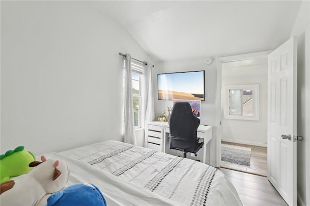 bedroom featuring vaulted ceiling, light wood-style floors, a desk, and baseboards