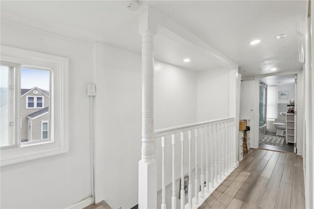 hallway featuring an upstairs landing, wood finished floors, and recessed lighting