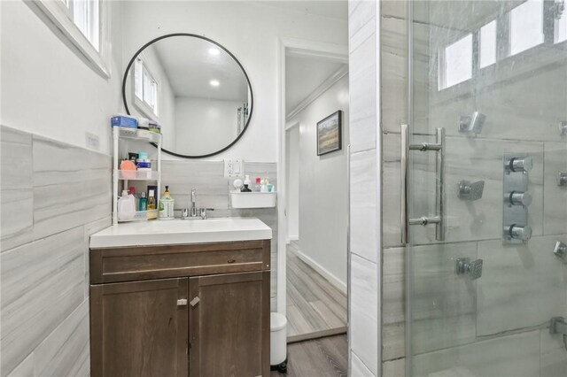 full bath with vanity, tile walls, wood finished floors, a shower stall, and healthy amount of natural light