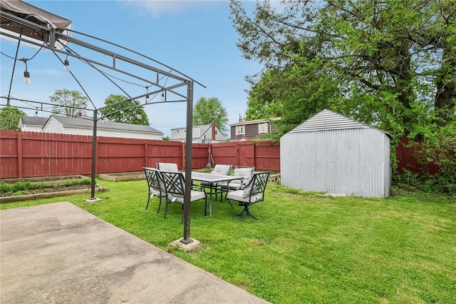 view of yard featuring a patio area, an outbuilding, outdoor dining space, and a storage unit