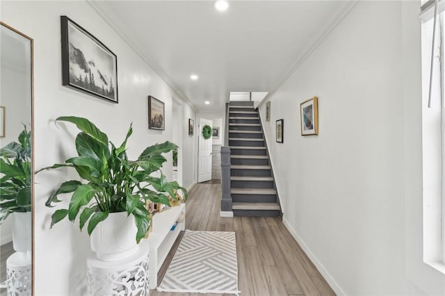 corridor with crown molding, light wood finished floors, stairs, recessed lighting, and baseboards