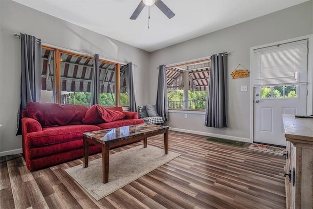 living area featuring baseboards, ceiling fan, and dark wood finished floors