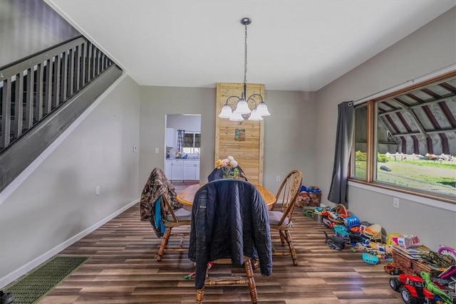 dining space with a chandelier, wood finished floors, baseboards, and stairs