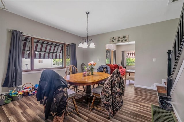 dining area featuring stairway, wood finished floors, a chandelier, and baseboards