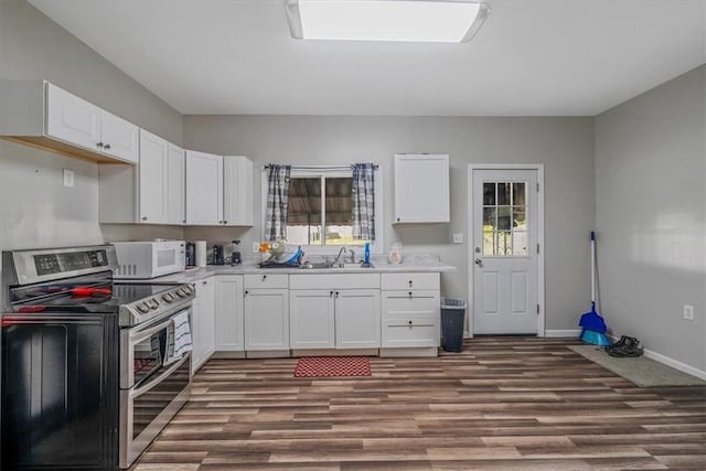 kitchen with range with two ovens, white microwave, dark wood-type flooring, a sink, and white cabinets