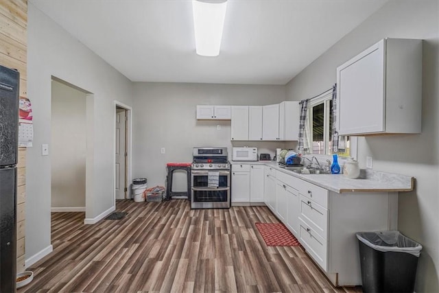 kitchen featuring double oven range, white microwave, a sink, and wood finished floors