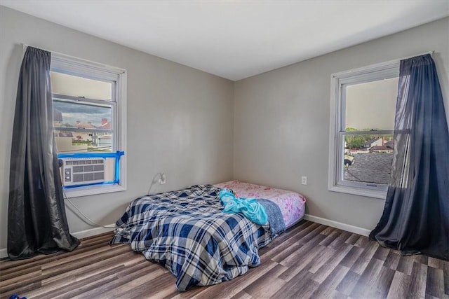 bedroom with wood finished floors, baseboards, and cooling unit