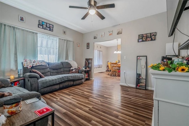 living area featuring a ceiling fan, a chandelier, wood finished floors, and baseboards