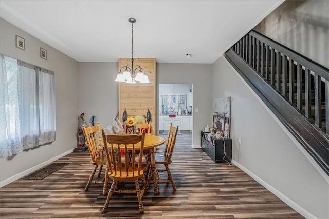 dining space with wood finished floors, a chandelier, baseboards, and stairway