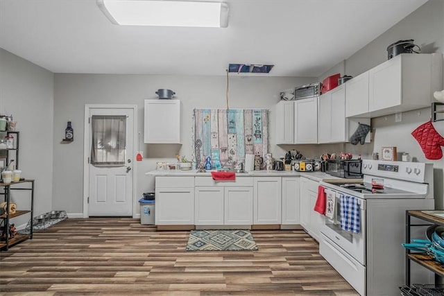 kitchen with electric stove, wood finished floors, white cabinetry, and light countertops