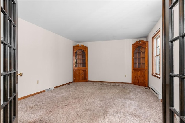 carpeted spare room with a baseboard heating unit and baseboards