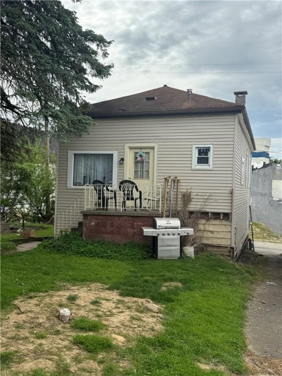 back of property with a yard and a chimney