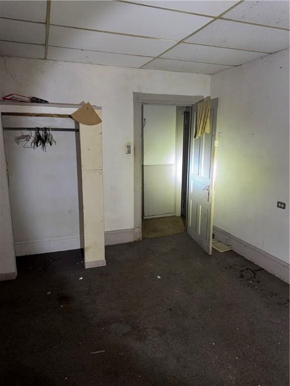 unfurnished bedroom with a drop ceiling and baseboards