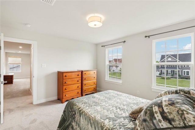 bedroom with light colored carpet, multiple windows, and baseboards