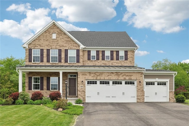view of front of house featuring asphalt driveway, brick siding, a standing seam roof, a front yard, and a garage