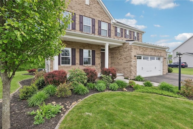 view of front of house with brick siding, a garage, a front lawn, and asphalt driveway