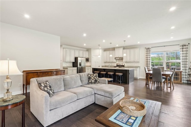 living area with recessed lighting, dark wood-type flooring, and baseboards