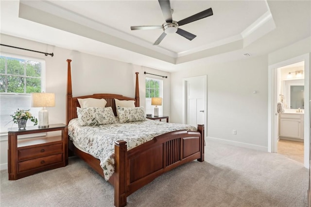 bedroom featuring a raised ceiling, light carpet, crown molding, baseboards, and a ceiling fan